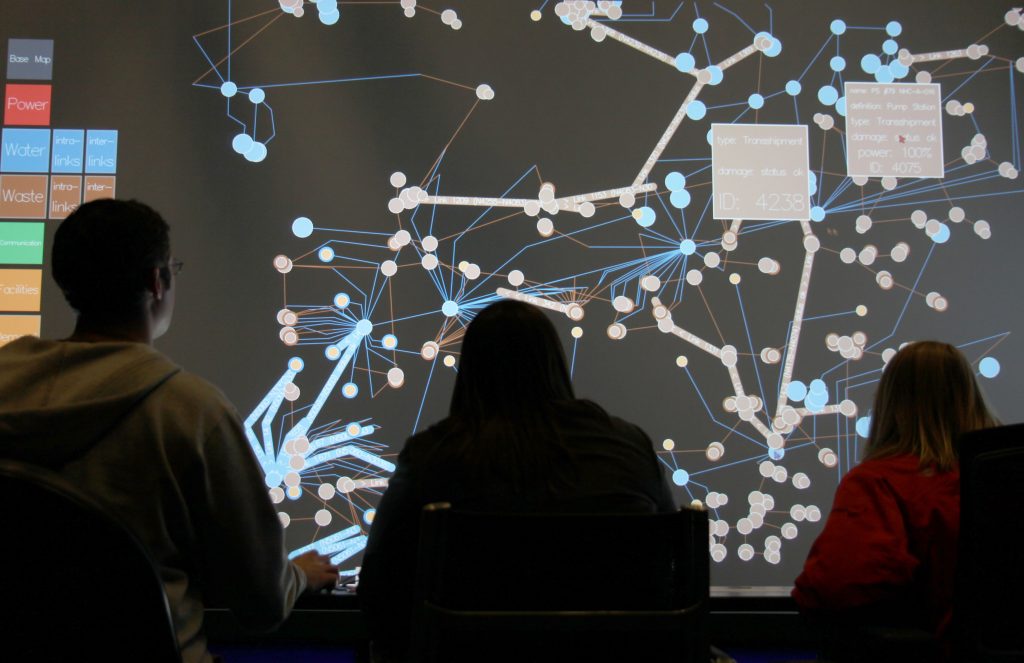 Students gathered round a large IT screen with an information map.